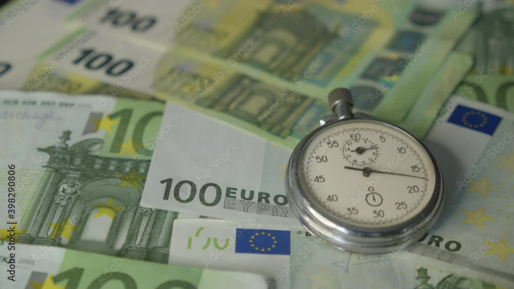 Close-up Of Stopwatch In Front Of Euro Banknotes Close-up Of Stopwatch In Front Of Euro Banknotes