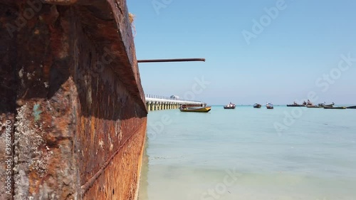 Looking toward the jetty of an andaman island from behind a rusty barge transport boat at low tide and high noon photo