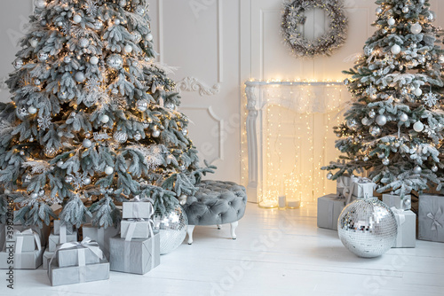 White decorated christmas room with two christmas trees, chimney, a lot of presents in country house