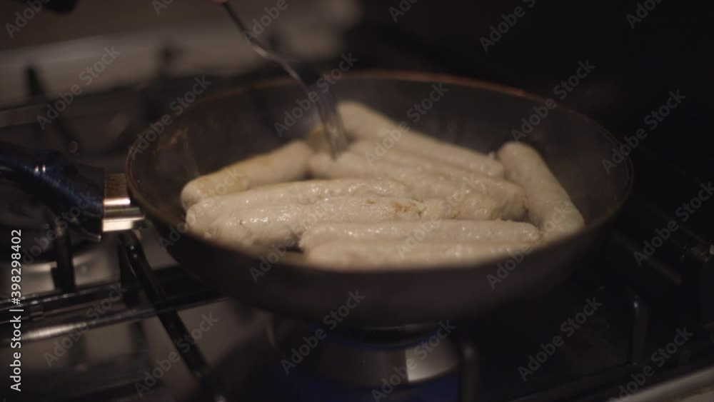 Man or woman prepare sausages in a pan. Cooking at home or restaurant, Tasty food. Closeup shot in 4k from right Man or woman prepare sausages in a pan. Cooking at home or restaurant, Tasty food. Closeup shot in 4k from right