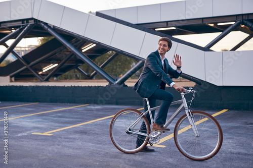 Trendy office employee on bicycle greeting friend in city