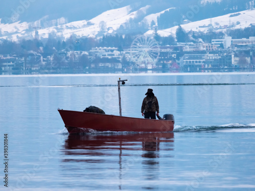 A fishing boat in the winter on the waters of the Upper Zurich Lake (Obersee), near the lakeside village of Hurden, Schwyz, Switzerland photo