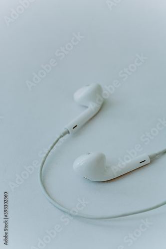Fototapeta Naklejka Na Ścianę i Meble -  in-ear headphones are wired. White wired headphones lie on a white background. The concept of modern technologies and gadgets. Minimalism, close-up. vertical photo