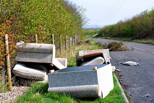 Waste dumped in the countryside, settee, sofa, parts of a tree, fly-tipping causing environmental pollution. Fly tipping.