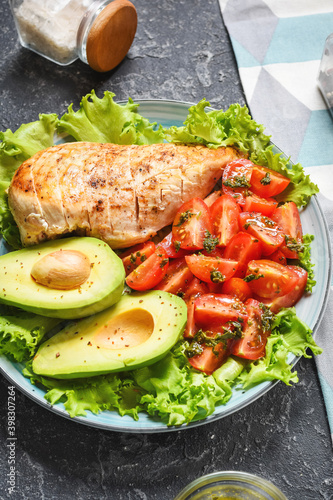 Caprese lunch bowl with grilled chicken and avocado on stone background