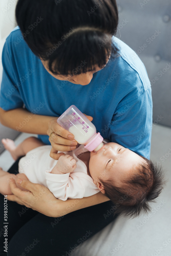 Asian loving mother feed her cute newborn baby while sitting on sofa. Asian loving mother feed her cute newborn baby while sitting on sofa.