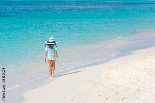 Young girl walking on a white sand Caribbean beach with beautiful water.