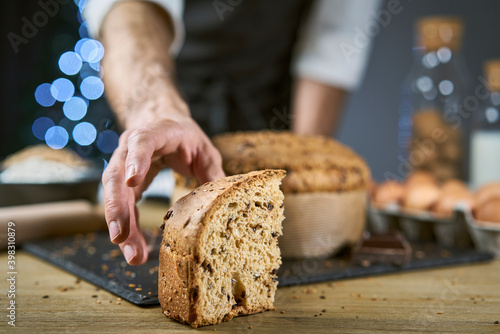 A man want to take a slice of freshly baked dessert, homemade with flour, eggs, cereals, oats, spelt, barley and chocolate. The cake is similar to a panettone and pandoro to celebrate the holidays tog