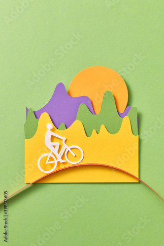 Papercraft cyclist is riding a bike outdoor. photo