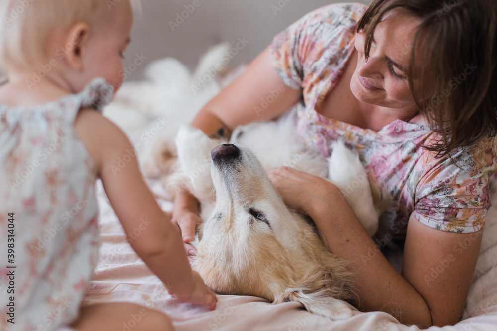 Mother and daughter patting golden retriever Mother and daughter patting golden retriever