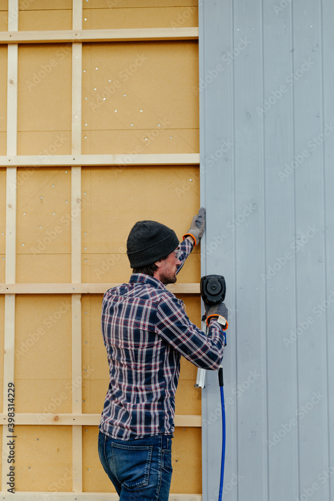 Man installing siding on house wall Man installing siding on house wall