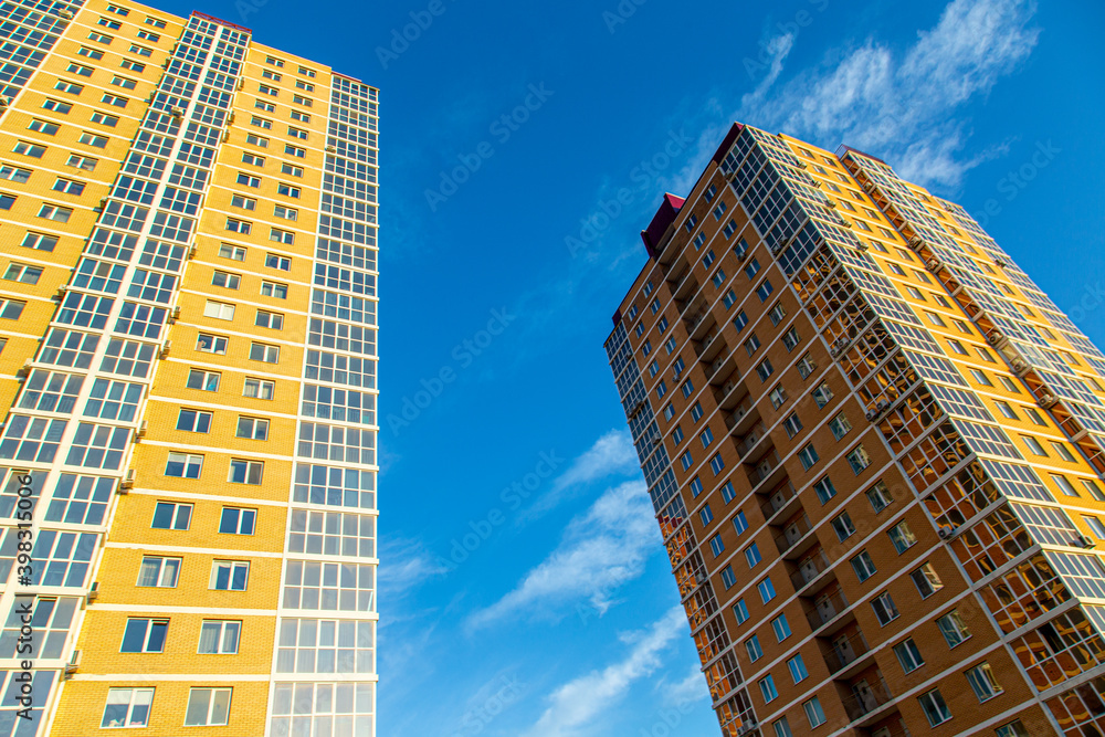 Obraz premium Modern multi-storey residential buildings made of bricks and glass against the background of the sky. In brown, beige. Construction.