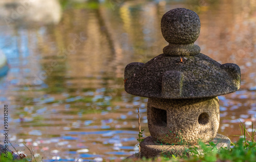 a stone birdhouse and park  trees and a lakeside. 