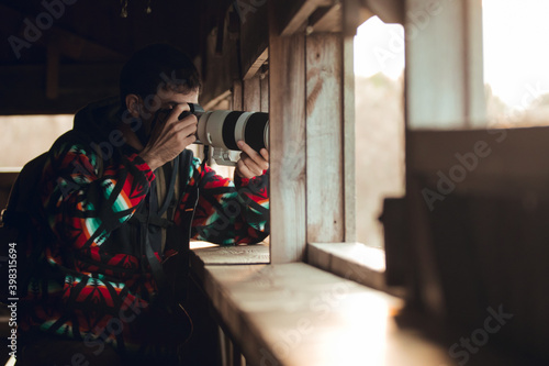 wildlife photographer hiding at home hide to take pictures of birds and wild animals