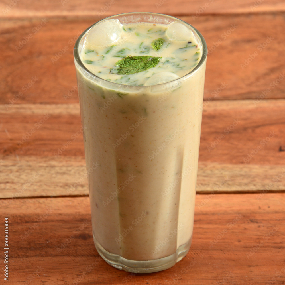 Masala Buttermilk drink or masala chaas, Made of yogurt. served in a glass over a rustic wooden background,a refreshing drink for summer days, selective focus on top Masala Buttermilk drink or masala chaas, Made of yogurt. served in a glass over a rustic wooden background,a refreshing drink for summer days, selective focus on top
