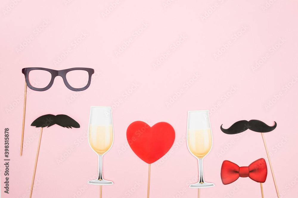 Valentine's day lgbt, love, romantic concept. Red heart, champagne glasses with couple paper mustache props on pink background. Greeting card. Flat lay, top view, copy space