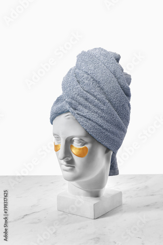Gypsum goddess with patches and towel on head. photo