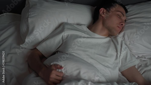 Calm handsome man goes to sleep in comfortable cozy fresh bed enjoying healthy good sleep nap.