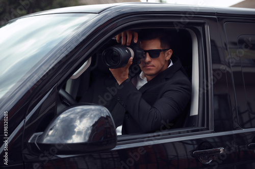 Private detective with camera spying from car