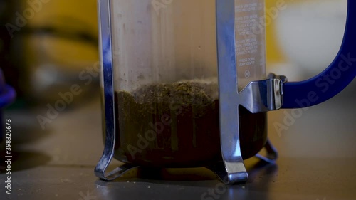 Filling a french press with water while making coffee, fresh ground beans inside photo