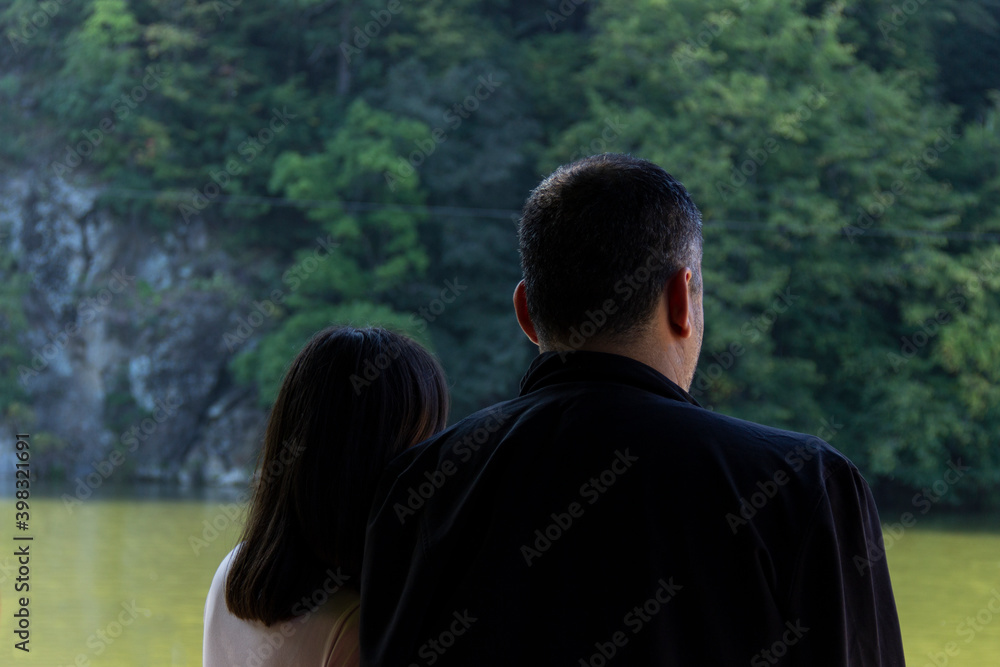 Back side of a peaceful couple standing in the forest, enjoying beauty of nature, love and togetherness concept. Back side of a peaceful couple standing in the forest, enjoying beauty of nature, love and togetherness concept.