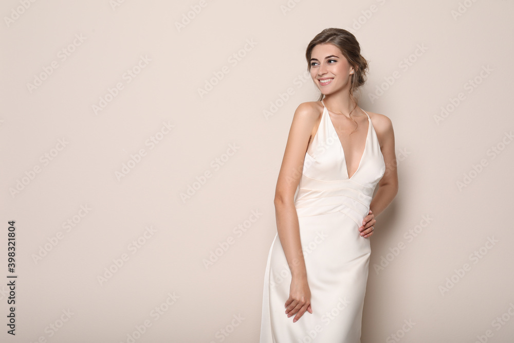 Young bride wearing beautiful wedding dress on beige background. Space for text Young bride wearing beautiful wedding dress on beige background. Space for text