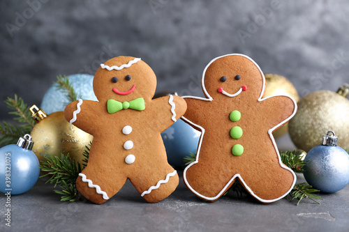 Gingerbread people and Christmas decor on grey table, closeup