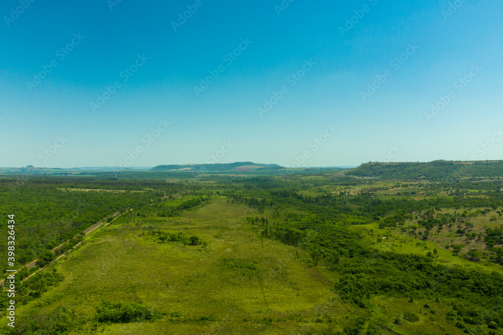 aerial view of area with woods beside highway and mountains in the background - Brazil