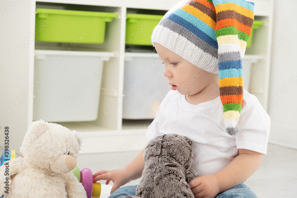 baby toddler boy in funny hat playing with teddy bear at home. Developing games for children. baby toddler boy in funny hat playing with teddy bear at home. Developing games for children.