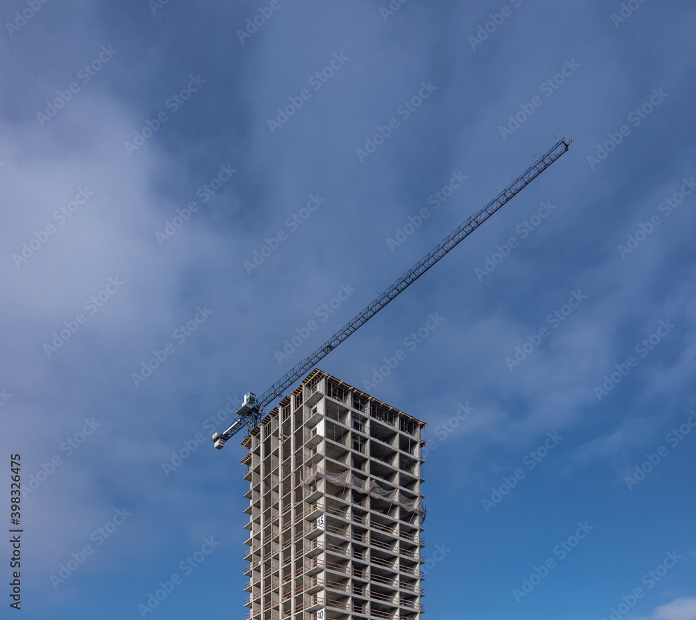 Fototapeta premium Building construction site with tower crane against blue sky