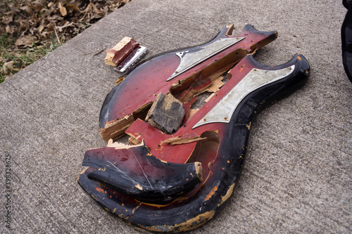 A broken red guitar on concrete