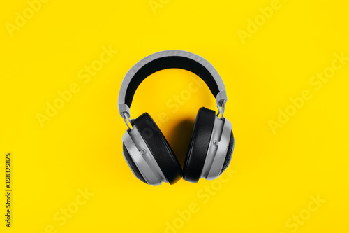 modern gray wired headphones on illuminating background, dj listening to music on headphones. color of year 2021