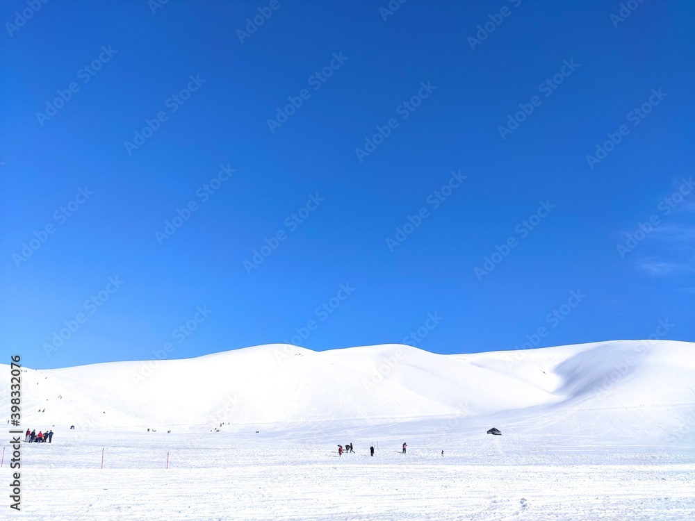 blue sky, snowy slopes and miniature people