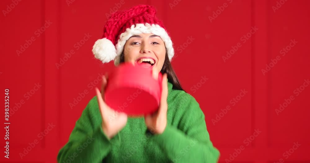 Cute young woman in Santa hat and with Christmas gift on color background Cute young woman in Santa hat and with Christmas gift on color background