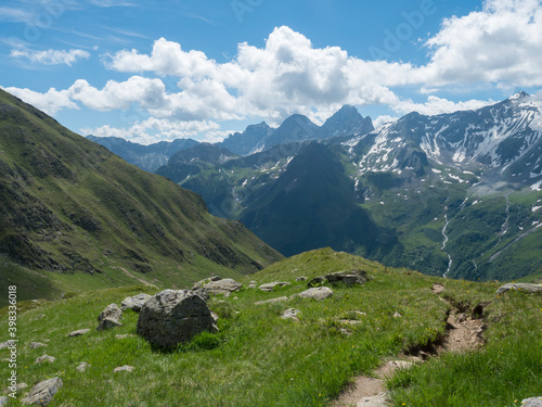 view on snow-capped moutains and green valley with winding spring stream and footpath of Stubai hiking trail, Stubai Hohenweg, Alpine landscape of Tyrol Alps, Austria. Summer blue sky © Kristyna