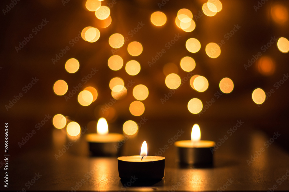 Burning candles on wooden table with blurred lights background