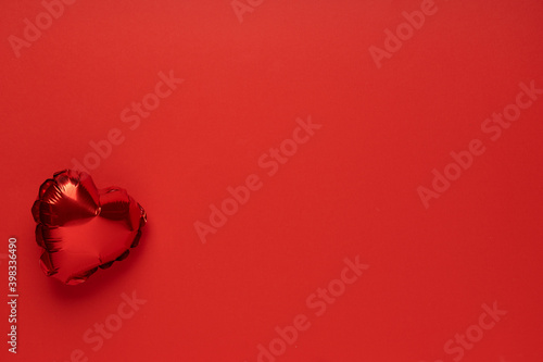 Red balloon in the shape of heart on red background top view flat lay copy space