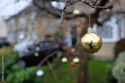 Foto Closeup wide shot of a small christmas ornament hung on a tree on the street in front of a family house