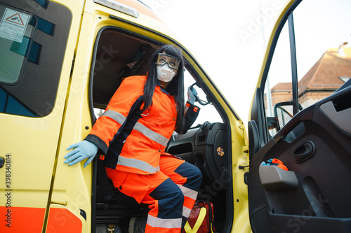 Epic superhero shot: Serious female paramedic sits at ambulance vehicle ready for action