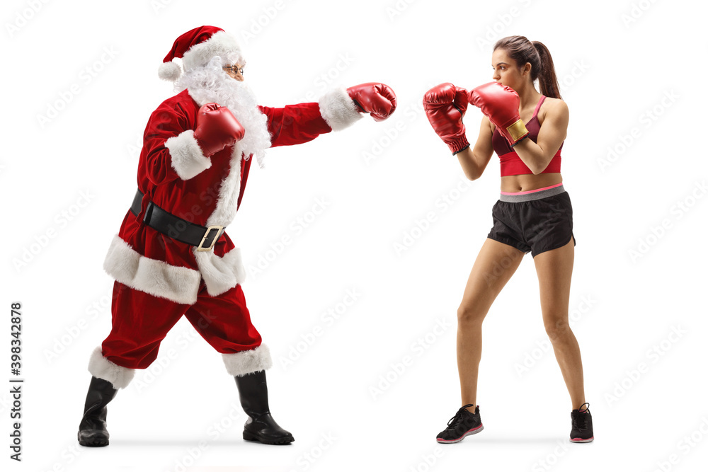 Full length profile shot of a young female boxer and santa claus punching with boxing gloves Full length profile shot of a young female boxer and santa claus punching with boxing gloves