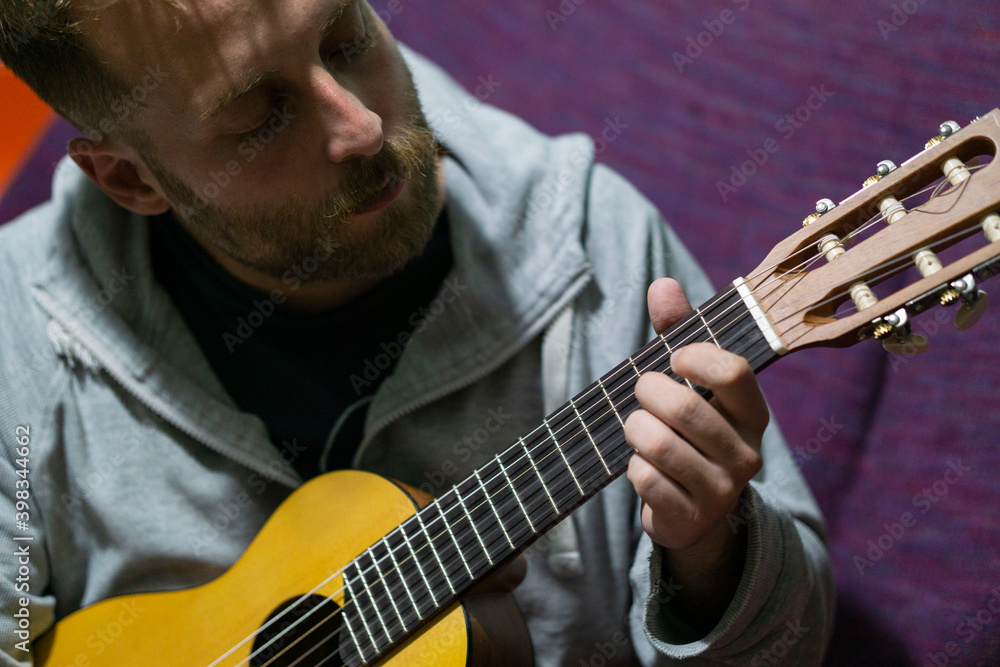 Obraz premium man playing ukulele at home