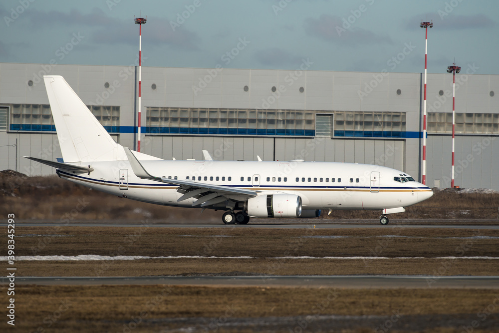 Fototapeta premium New moodern private jet white airline landing at an airport. Tthe engines are reversed for braking.