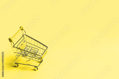 Empty shopping cart on bright illuminating yellow background with copy space with selective focus. Discount and sale concept. Color trend of 2021 concept
