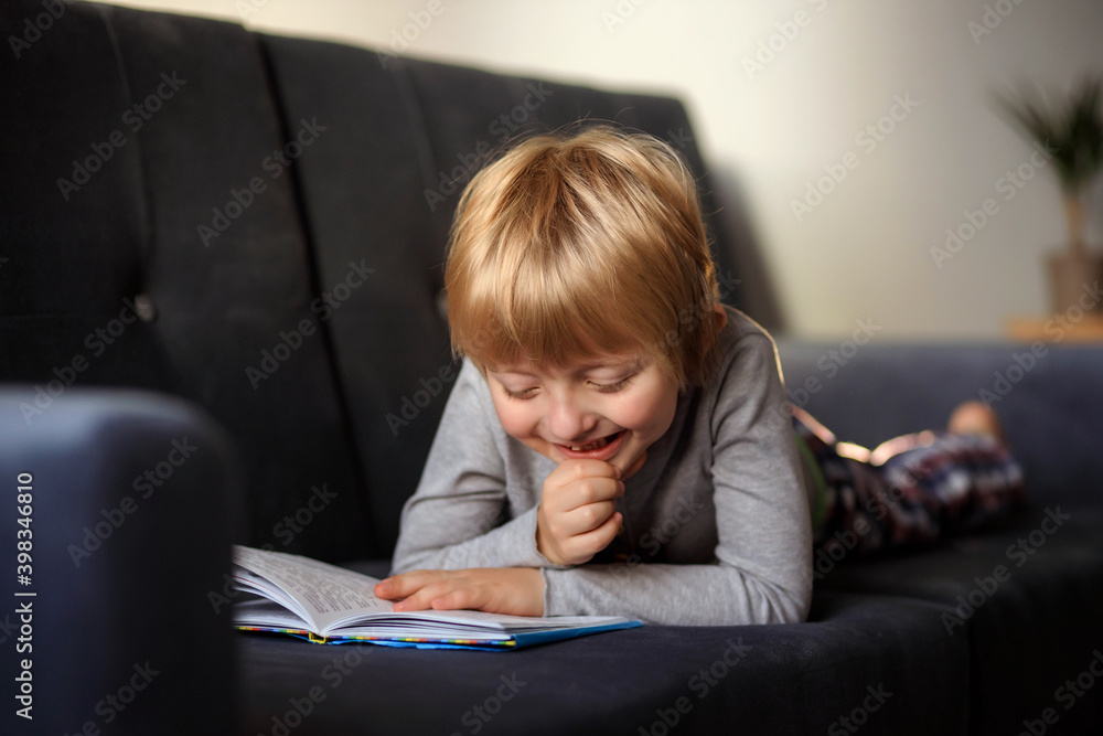 Child little boy reading a book while lying on the sofa Child little boy reading a book while lying on the sofa