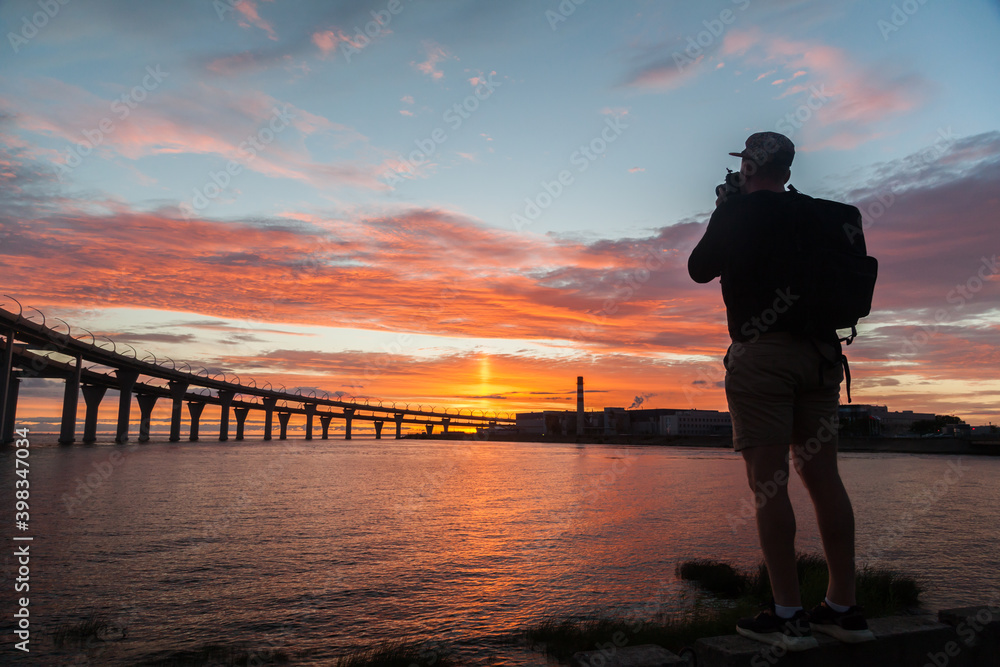 Fototapeta premium Silhouette of man making photo of highway bridge in sunset time