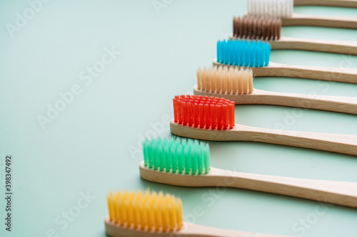 A set of Eco-friendly antibacterial toothbrushes made of bamboo wood on a light green background. Environmental care trends