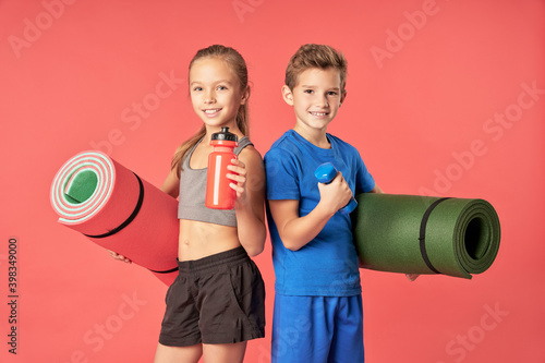 Fototapeta Naklejka Na Ścianę i Meble -  Joyful kids with sports equipment standing against red background