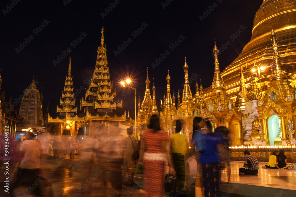Fototapeta premium a group of people standing in front of a lit up building at night