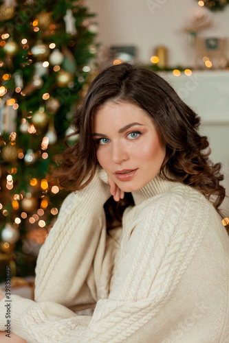 Christmas. Portrait of a young beautiful woman by the Christmas tree. A young woman opens a gift box. Holidays.
