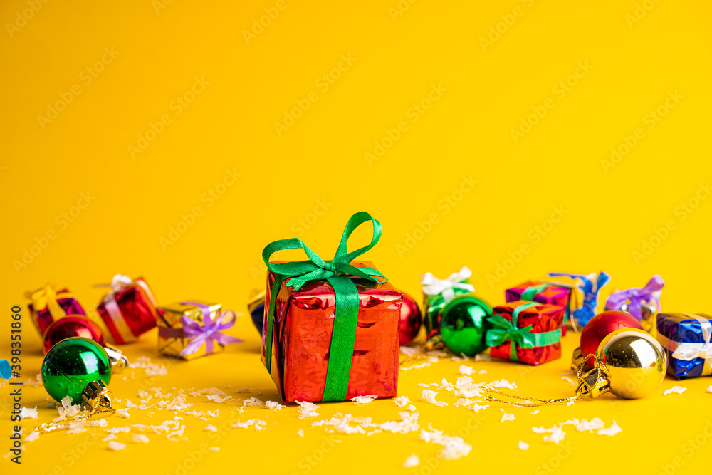 Gift box with a Christmas present on a yellow background, among the New Year's decorations